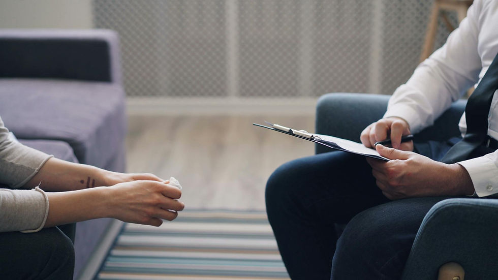 A therapy session with a psychologist and patient, discussing mental health indoors.