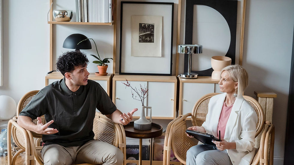 A man and woman in discussion in a modern living room with wooden chairs and artistic decor.