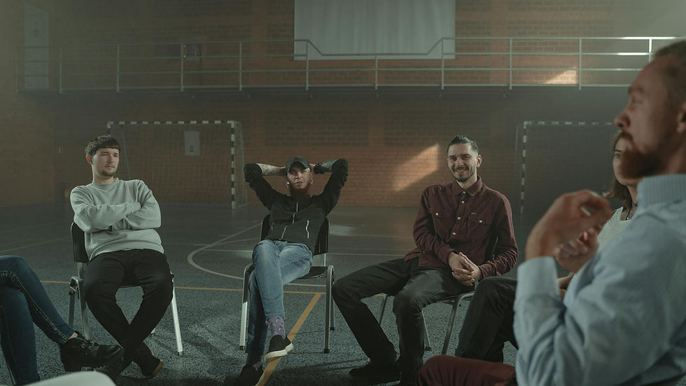 A group of adults engaging in a therapy session in a spacious gymnasium setting.