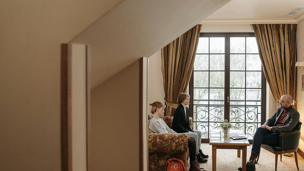 Counselor meeting with two clients in a warm, well-lit office setting.