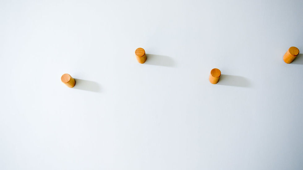 Simple arrangement of wooden pegs casting shadows on a stark white wall.