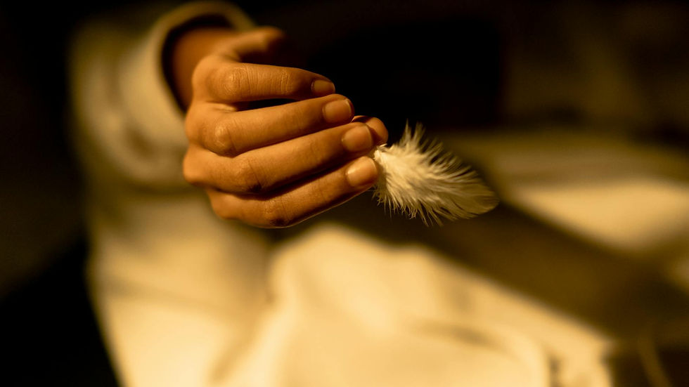 Close-up of a hand delicately holding a white feather, creating a serene and peaceful atmosphere.