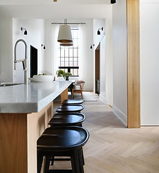 Minimalist kitchen with waterfall island and modern bar stools, highlighting luxury finishes in a Toronto home