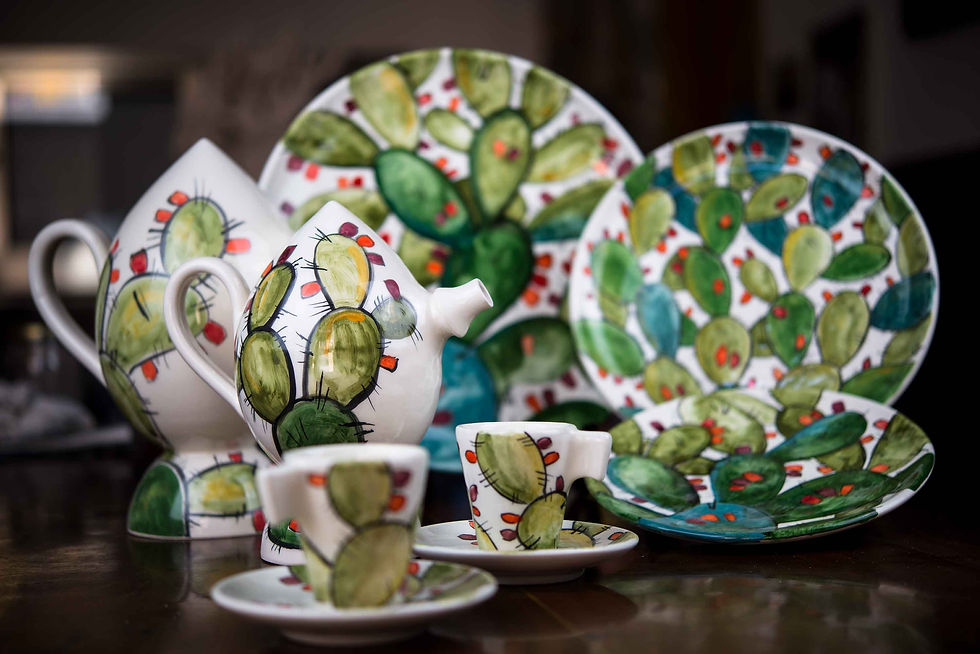 Close-up of hand-painted Sicilian ceramic plates stacked on a rustic wooden shelf