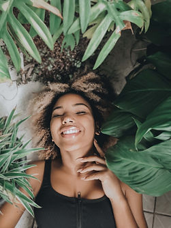 Une femme allongée autour de plantes vertes.