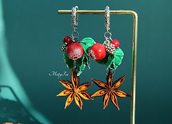 Handmade red berry and star anise earrings on a display stand