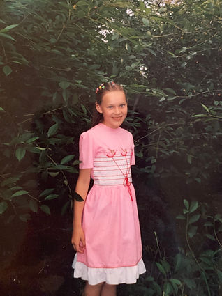 Young Mary in a pink dress standing outdoors