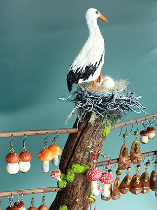 Miniature mushroom earrings displayed around a stork figurine