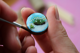 Hand painting a tiny forest landscape on a round miniature