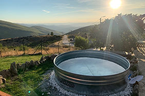 Sunlit mountain valley with a round water trough in the foreground