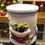 Thumbnail: Hand-painted cement candle with colorful presents and chimney design, lit Christmas tree softly blurred in the background.