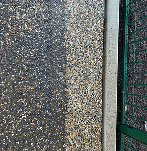 Close-up view of a concrete surface showing a dramatic before-and-after effect from pressure washing, highlighting the effect