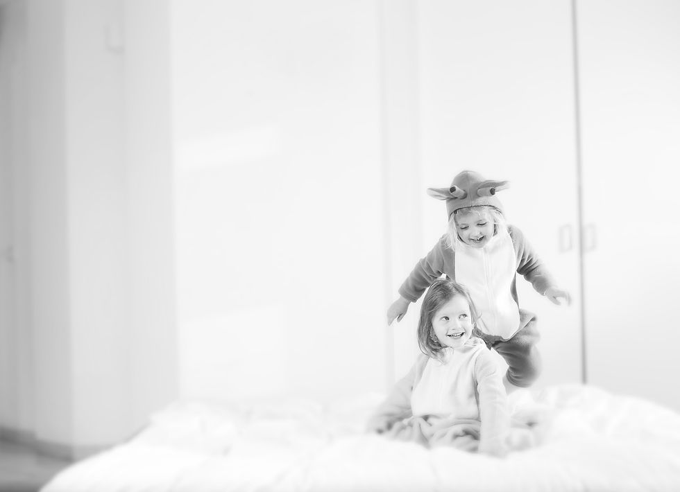 Two little children laughing on a bed