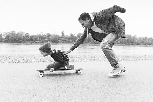 A single father pushing his son on a skateboard