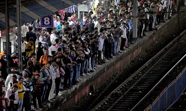 Commuters crowd on a platform as they wait to board suburban trains at a railway station in Mumbai