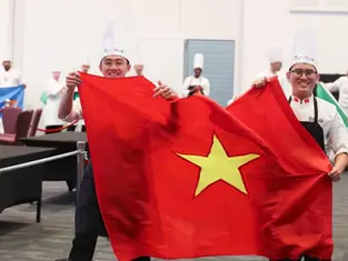 Chefs Le Dac Minh Quan (L) and Trinh Tuan Dung hold the Vietnamese flag at the Global Chefs Challenge 2026's final