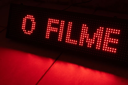 O filme já vai começar' (2025) de Rafa: painel LED vermelho 70x20cm evocando letreiros clássicos de cinema, com a frase: O FILME JÁ VAI COMEÇAR. 