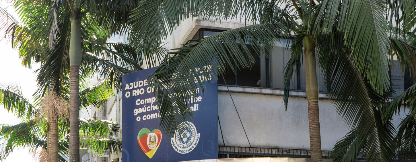 Fotografia atual da fachada do Café Aquarius, na esquina das ruas XV de novembro e 7 de setembro, onde antes se localizava o cinema Ponto Chic. O prédio é alto, apresentando muitos andares, e o café aquarius apresenta fachada com grandes portas e janelas envidraçadas. 