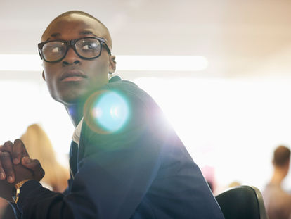 A young African professional man sitting in a seminar, listening attentively, symbolizing the impact of strategic bursary management under B-BBEE policies as discussed in the article 'B-BBEE Strategic Bursary Management.