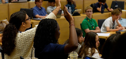 A student raising her hand to answer a question in an Oxford seminar