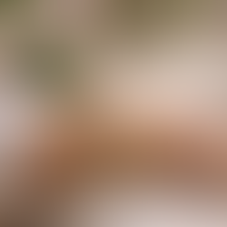 Wrist adorned with gold vintage bracelets and a diamond band, set against a blurred floral background. A white cup on the table adds elegance.