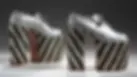 Pair of silver vintage platform heels with black-and-gold striped studded soles on a grey studio background. They originally belonged to Sir Elton John.