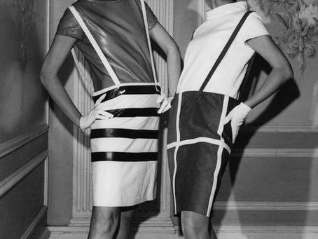 1960s photo of fashion models posing for Courrèges in geometric black-and-white dresses and white caps in a formal room.