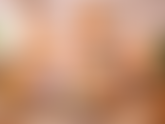 Cozy bedroom with a colourful bedspread, pillows, and plants. Warm lighting from lamps. Art on walls includes rainbow and flower prints.