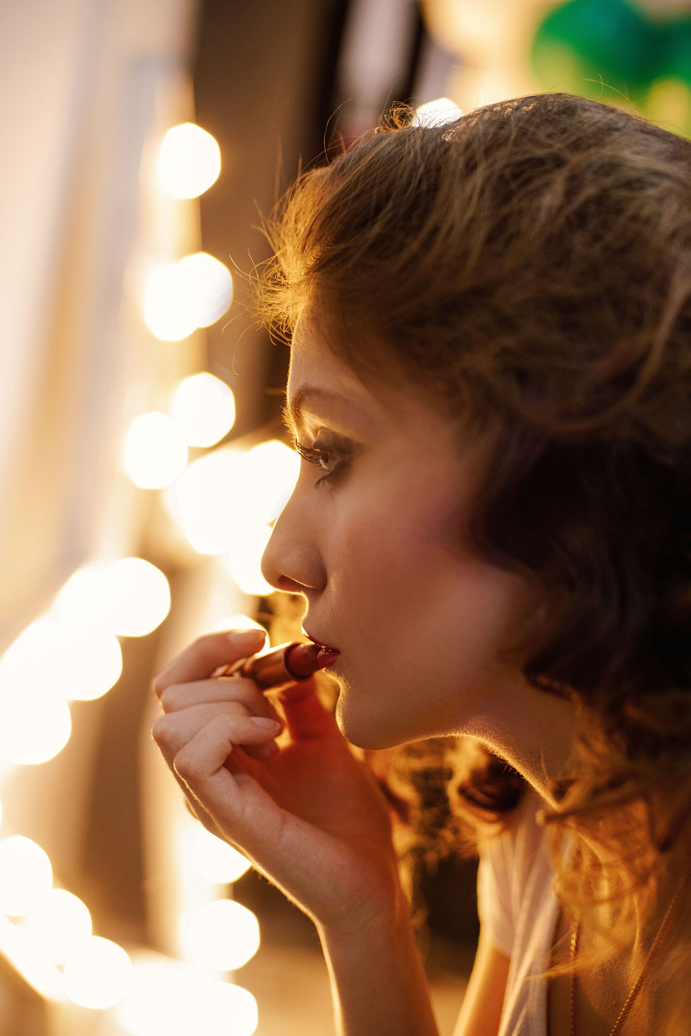 Woman applying red lipstick while looking into a mirror