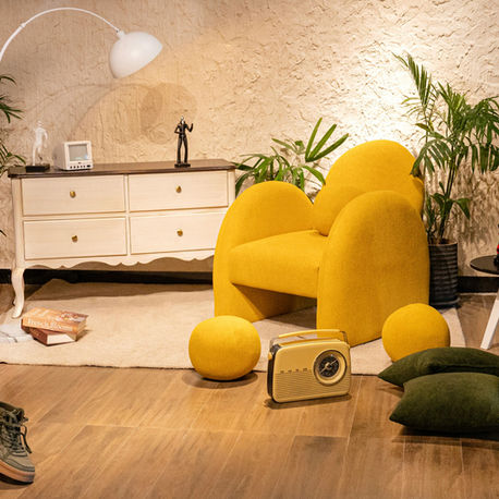Cozy vintage living room with a yellow chair, vintage radio, and plants. Beige textured walls, white lamp, and abstract art create a retro vibe.
