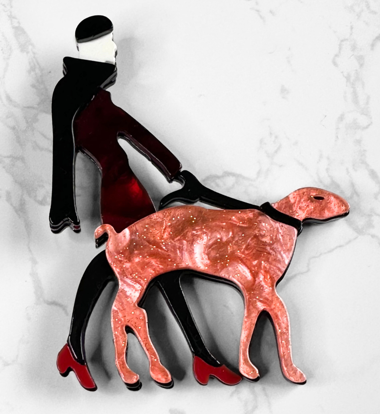 Acrylic novelty brooch of a stylish lady walking a pink dog