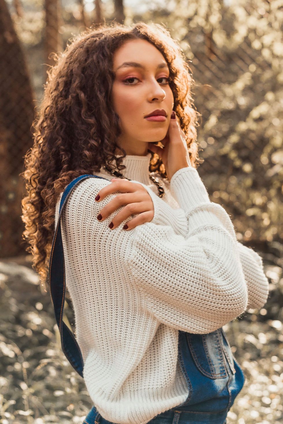Woman styling a cream knitted jumper with denim for a simple modern outfit inspired by vintage knitwear.