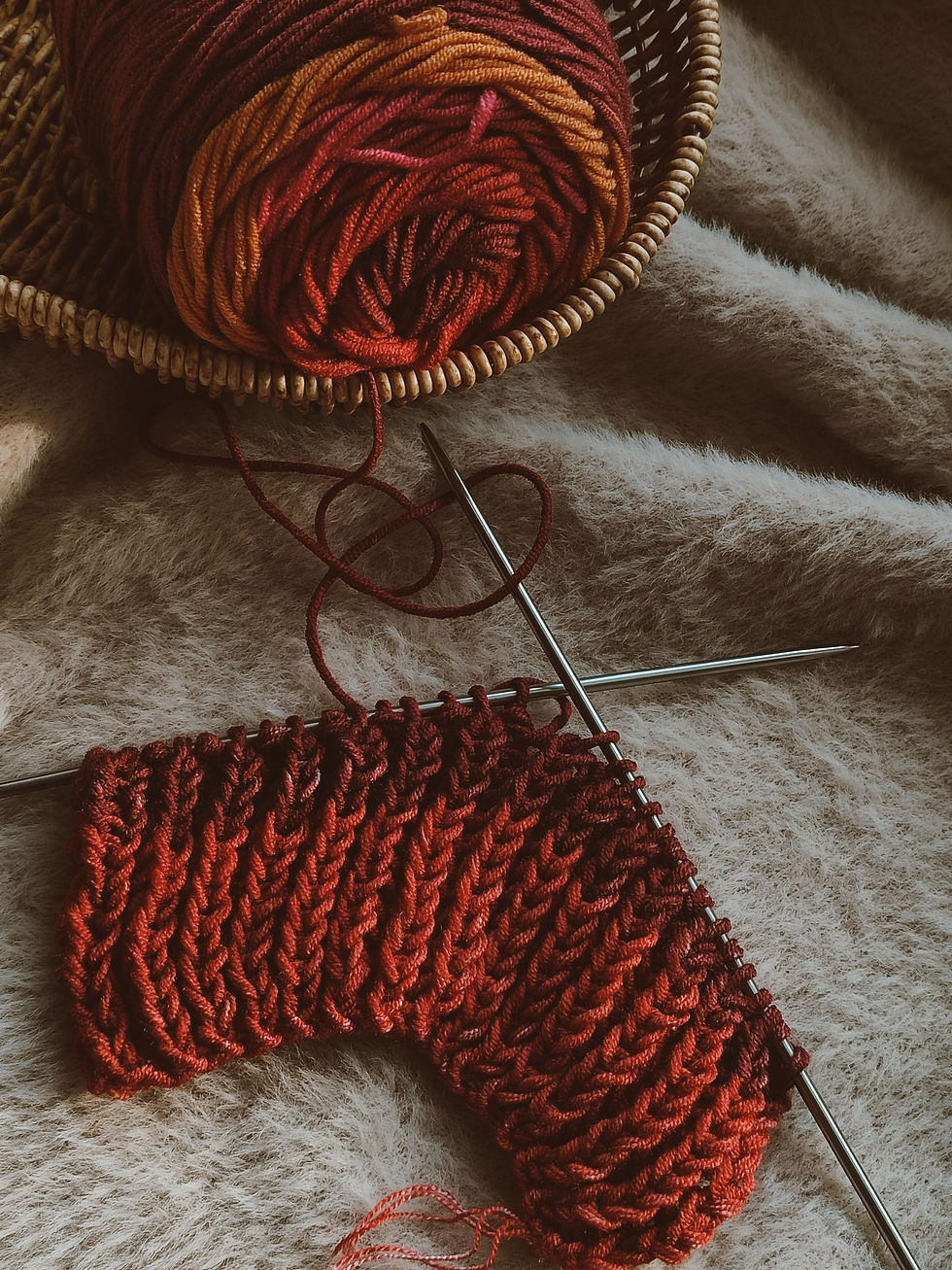 Burgundy yarn and a partially knitted cable pattern on knitting needles, reflecting the traditional techniques behind vintage knitwear.