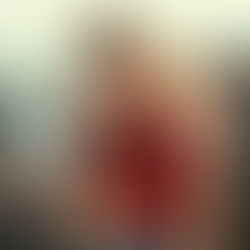 Woman in red sequined top holds a disco ball, surrounded by light reflections. Her expression is contemplative, against a modern interior.