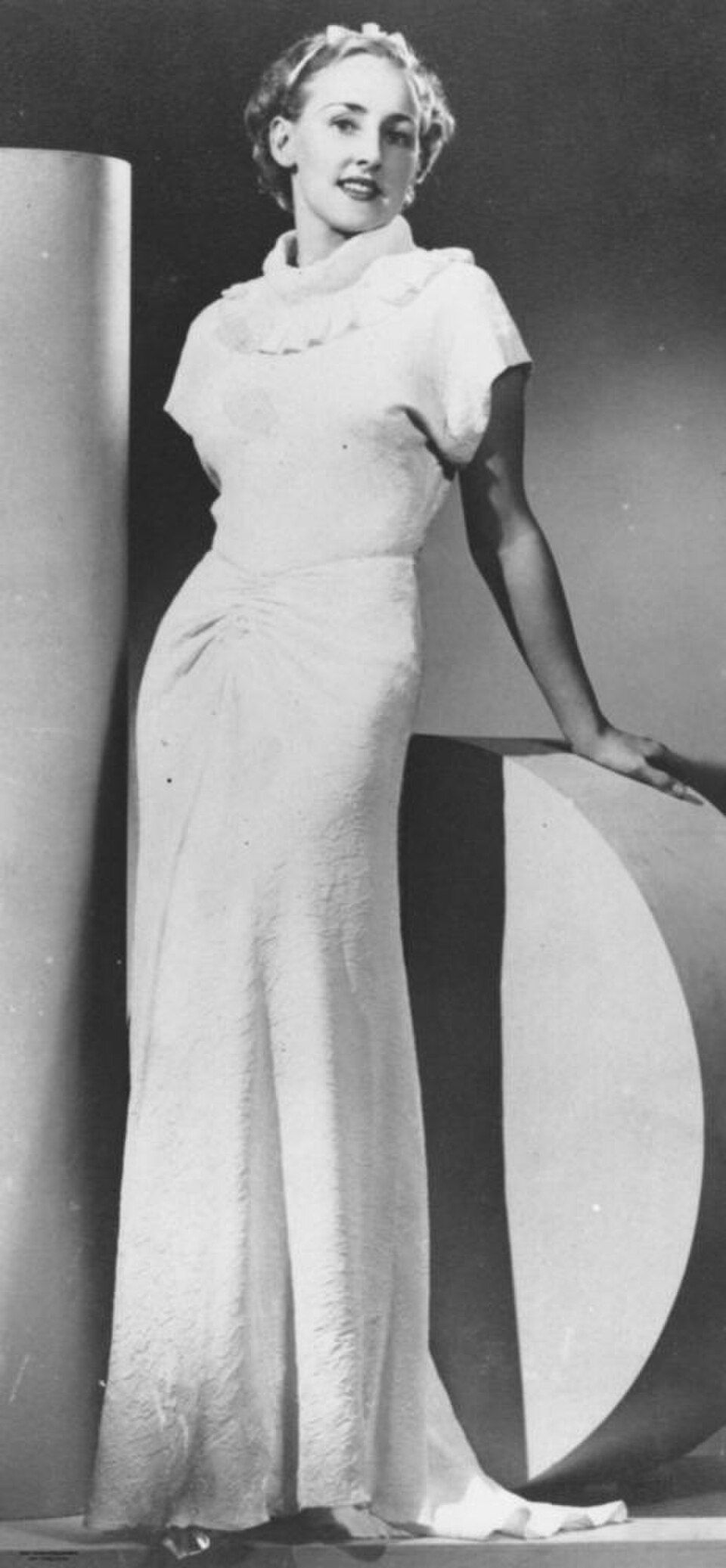 Woman modelling a long fluid 1930s evening gown with a body-skimming silhouette