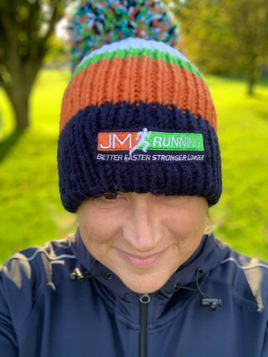 Close-up shot of the official JM Running team bobble hat featuring the run club logo.