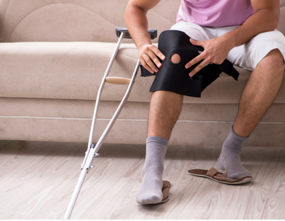 Patient at home with knee injury sitting on settee with crutch