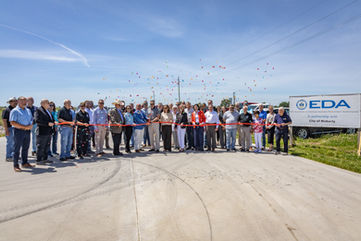 Ribbon cutting with large group of people by EDA sign