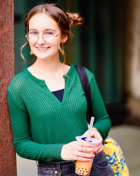 High school senior portrait in St. Paul, MN of a young woman with glasses wearing a green top and holding a bubble tea with tapioca pearls. Photography by Bonni Allen.