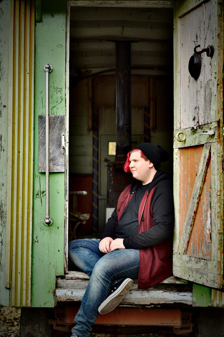 A young man's high school senior picture with him standing in an open doorway of an old building. Photo credit Bonni Allen Photography.