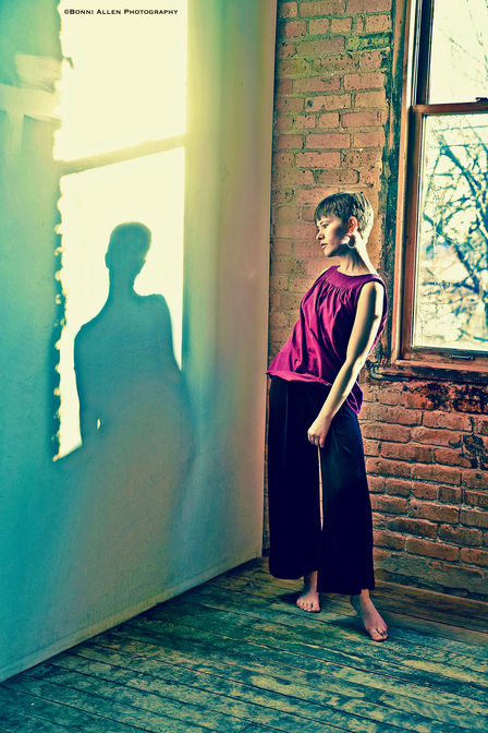 Artistic senior portrait of a young woman looking at her shadow framed by sunlight. Inspiration and photo credit by Bonni Allen.