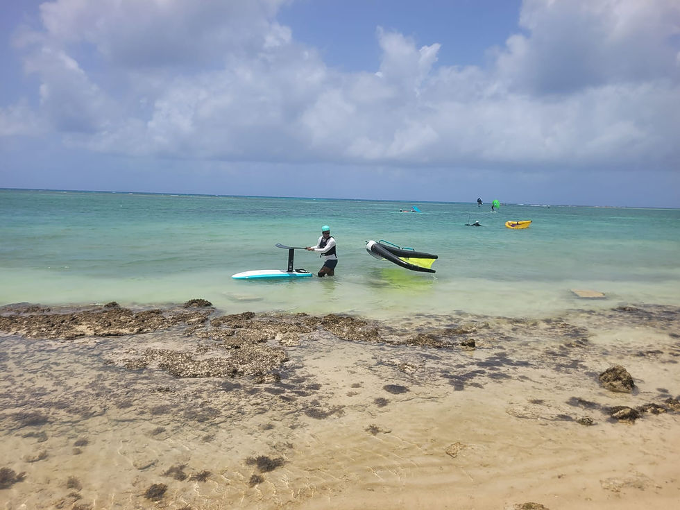Pratiquant de wingfoil sortant du lagon de La Coulée, spot idéal en Guadeloupe pour apprendre et progresser sans sargasses, avec un plan d’eau sécurisé.