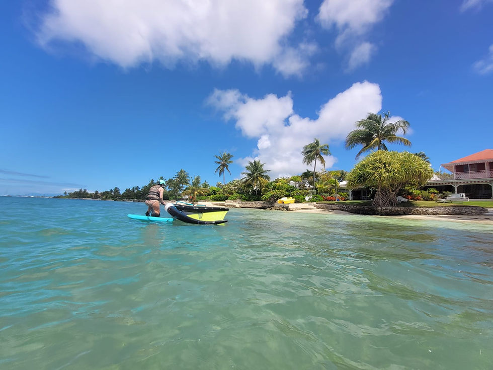 Une élève en wingfoil sur le lagon de Saint-François, devant les villas de La Coulée en Guadeloupe, lors d’un cours de wingfoil débutant.