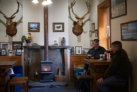 Locals+enjoying+a+beer+and+a+chat+by+the+fire+at+Stanley's+Hotel.webp