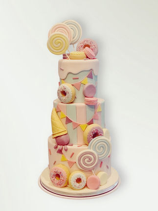 Three tier candyland cake decorated with lollipops, ice cream and bunting