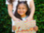 Little girl holding up her rainbow artwork book made with Artkive. This rainbow painting was made outlining the word "Love".