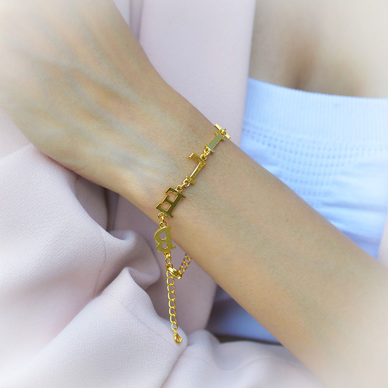 Close-up of a gold personalized initial charm bracelet on a wrist