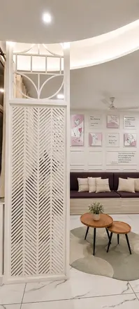 Decorative partition overlooking the waiting lounge at Ekam.Her Women's Health Clinic featuring custom seating, organic rug, wooden nesting tables, indoor plants, and contemporary women's healthcare interior design.