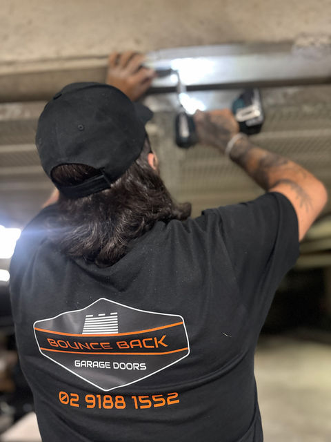 Technician servicing a garage door opener motor inside a Sydney garage