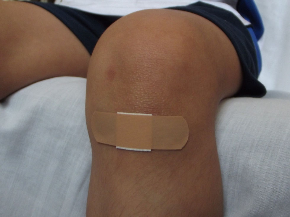 A leg hanging over the edge of a be with a plaster on the knee.